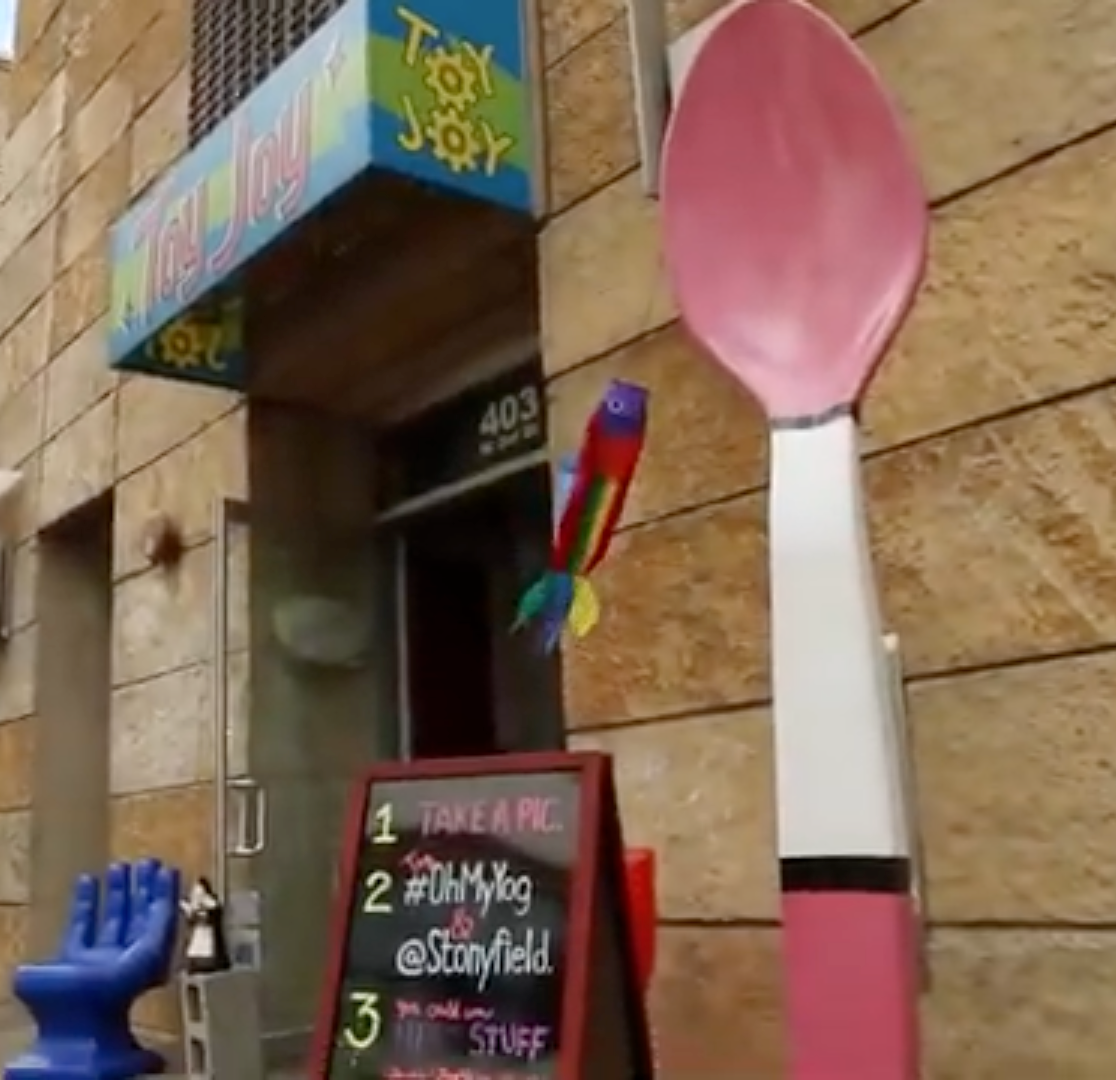 Oversized pink spoon prop installed outside Toy Joy storefront in Austin